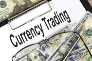 Financial concept image showing US dollar bills around a clipboard with the words 'Currency Trading'